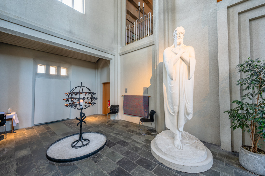 The interior of a church featuring the same candle display and Jesus statue as the previous image.